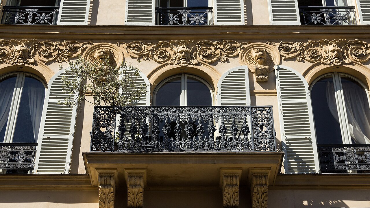 Balcon en fer forgé finement ouvragé sur une façade haussmannienne