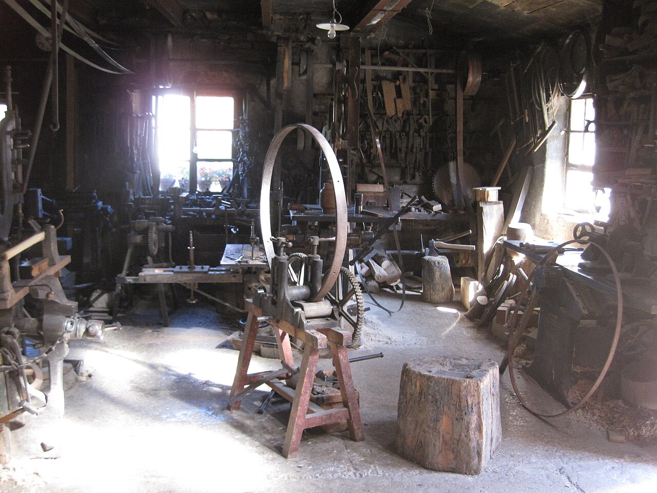 Intérieur d'un ancien atelier de forgeron avec outils, établis et cercle de fer